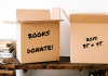 Spring cleaning, stack of books and cardboard boxes marked "Books Donate" and "Boys 3T and 4T"