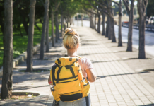 girl walking down road with yellow backpack