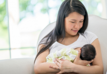 woman smiling and breastfeeding her newborn in a bright room