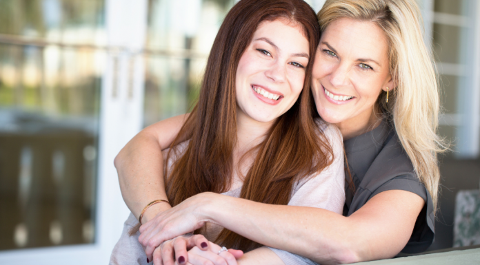 Mom and teen daughter, Mom is embracing daughter and both are smiling.