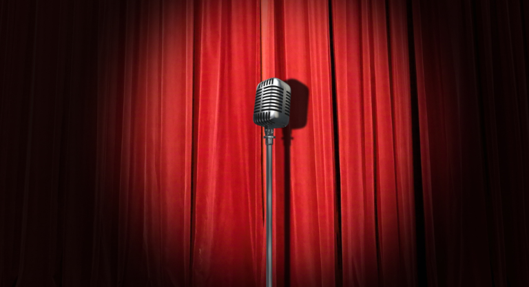 An old-fashioned microphone stands in front of a red curtain
