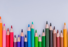 row of colored pencils with light grey background