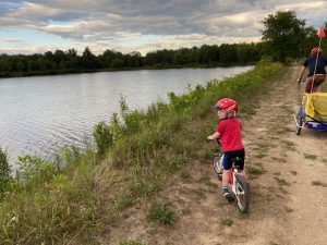 little boy on bike looks out over pond